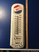 Full view of vintage Pepsi metal thermometer on blue background with ruler showing length.
