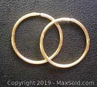 Clear close-up image of two small 10K gold slepper hoop earrings on a dark background, showing the polished finish and circular shape.