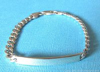 Full view of the silver ID bracelet showing chain and ID plate on blue textured background.