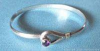 Front view of the silver and brass bangle showing the round purple amethyst stone and the wire wrapped loop design.
