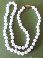 Full view of 17 inch Akoya pearl necklace with gold filled clasp on green background