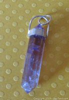 Long faceted purple amethyst pendant with sterling silver cap and bail, approx 1.5 inches long, showing inclusions inside the stone.