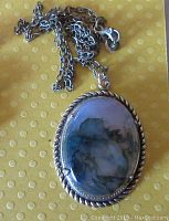 Close-up photo of the front of the moss agate pendant set in a rope pattern brass bezel, showing the stone's natural moss-like inclusions.