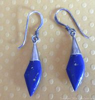 Close-up photo of a pair of sterling silver dangling earrings with deep blue lapis lazuli stones containing gold flecks, approximately 1.5 inches long, with silver hooks and caps.