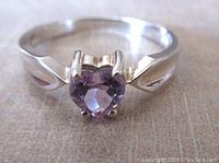 Close-up front view of vintage sterling silver ring with heart-shaped light amethyst stone set in prongs on a split shank band.