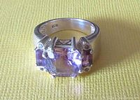 Front angle of the sterling silver amethyst ring showing three stones and wide band.
