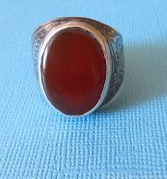 Front view of the ring showing the large oval carnelian cabochon mounted on sterling silver with visible black enamel designs on band sides.