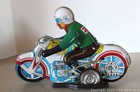 Side view of the vintage tin wind-up motorcyclist toy, showing colorful graphics and wind-up key on the side.