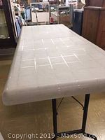 Top view of one white plastic folding table showing textured grid pattern surface.