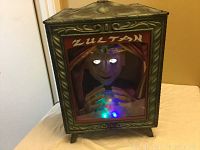 Front view of Zultan animated fortune teller in decorative cabinet with sculpted figure, lighted eyes, and colored crystal ball.