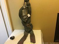 Full view of the ghoul figure seated on a table showing the entire body length and hanging arms