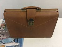 Front view of brown leather attache case with lock and handle showing exterior condition.