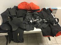 Overview of wetsuit, hood, gloves, booties, fins, regulator and carry bag arranged on table