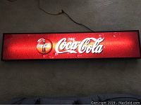 Full view of the large rectangular illuminated Coca-Cola sign. Shows size and lighting effect.