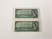 Two Canadian Centennial dollar bills, front side visible, featuring Queen Elizabeth II and denomination details.