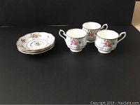 Photo of three Royal Albert Petit Point bone china tea cups arranged next to three matching saucers on a black background.