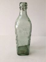 Full vertical view of the antique glass whiskey bottle showing its blue-green tint and rectangular shape.