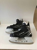 Pair of black and silver CCM Rib XT men's ice hockey skates, lightly used condition, showing side profile with white blade holders and blades.