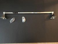 Chrome 24 inch towel bar with mounting hardware on black background
