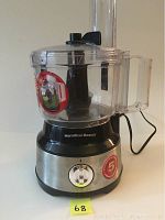 Front view of the food processor unit showing stainless steel base, control dial, and transparent plastic bowl with feeding chute and lid.