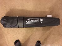 Black carrying bag with Coleman logo for folding chair storage and transport.