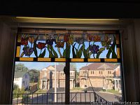 Full view of the installed stained glass panel above a window frame showing the multicolour floral design