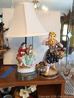 Overall view of both the lamp and the ceramic figurine on a wooden surface.