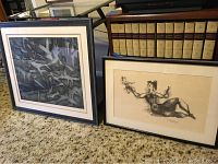 Two framed lithographs displayed side by side against bookshelf