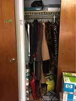 Closet full of varied coats and jackets along with handbags and boxes visible at floor level