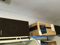 Realistic speaker next to an Onkyo TX-8020 receiver box on a shelf.