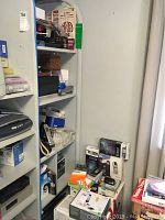 Shelf with office supplies including analog and cellular telephones, calculators, and boxes.