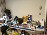 Wide view of table with various electronic items, cameras, accessories, cables, and packaging displayed.