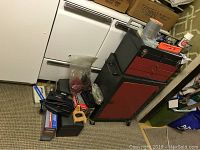 Overview photo showing the red and black toolboxes, stacked, with some boxed tools and parts on floor around it