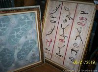 Photo of two framed Sheila Rosenfield prints featuring abstract designs; left print with green and blue tones, right print with red and black glyph-like markings.