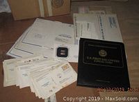 Lot items spread on floor including booklet, envelopes, and gold replica stamp case