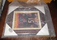 Framed signed print wrapped in protective bubble wrap.