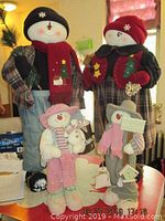 Four snowman family figures displayed on a table, showing full body and outfit details.