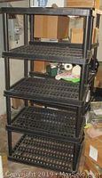 Full view of the black 5-shelf hard plastic shelving unit with grid shelves showing overall shape and structure.
