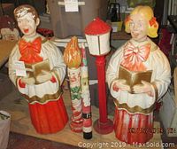 Front view of male and female carolers with candle and lamp post decorations behind