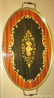 Top view of oval serving tray showing inlaid floral wood design with gold metal trim and handles