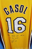 Close-up photo of the back of the jersey showing PAU GASOL lettering, number 16, and autograph with Spanish dedication.