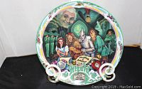 Front view of musical plate featuring main characters from The Wizard of Oz with title and musical song name.