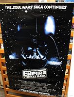Front of the original 1983 Star Wars The Empire Strikes Back poster showing Darth Vader and movie credits in a black starry background.