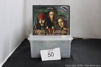 Photo of DVDs including Pirates of the Caribbean: Dead Man's Chest DVD displayed on top of a white plastic container with a lot number 50 tag.