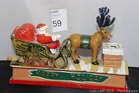 Front view of antique cast iron penny bank featuring Santa Claus and reindeer with holiday decoration