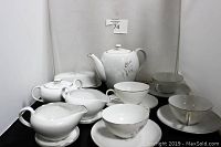 Photo of the full 18-piece fine china tea set showing teapot, sugar bowl, butter dish, teacups, saucers, creamers, and condiment dishes with silver floral decoration