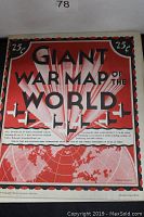 Close-up photo of the map's title area showing 'GIANT WAR MAP OF THE WORLD' with a red and black design, airplane images, and 25 cent price markings in corners.
