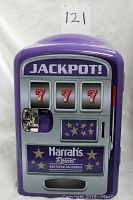 Front view of purple car fridge designed like a slot machine with 'JACKPOT!' label and triple 7 slot reel display, Harrah's logo at bottom.