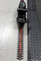 Full view of the Black & Decker electric hedge trimmer on the floor showing handle, blade, and cutting teeth.