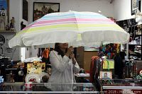 Person holding open the large umbrella showing the striped canopy in blue, pink and yellow with scalloped edges.
